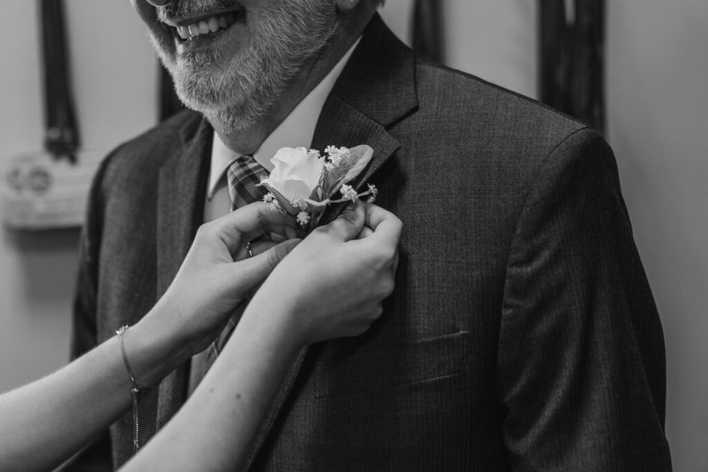Bride pinning boutonniere on father