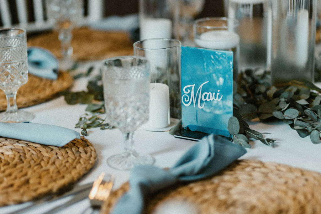 Elegant place settings featuring soft blue hues, greenery, crystal glassware and natural fiber place mats. 