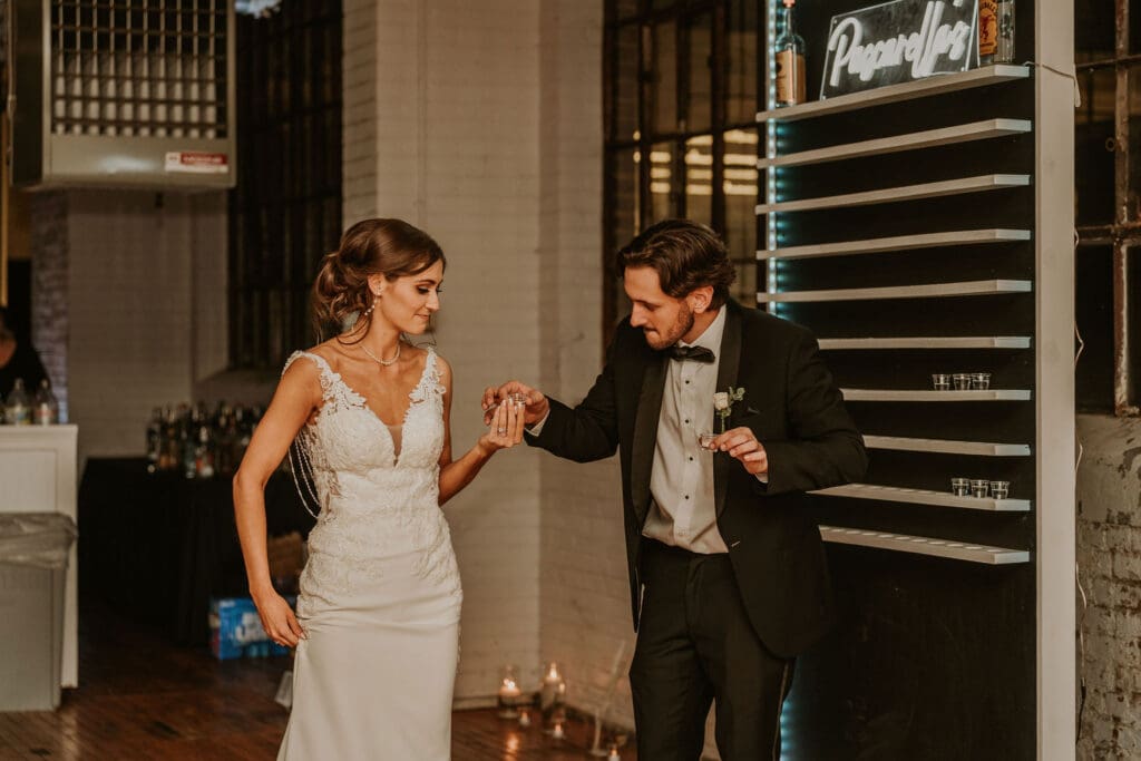 Couple taking shots off the shot wall during the reception